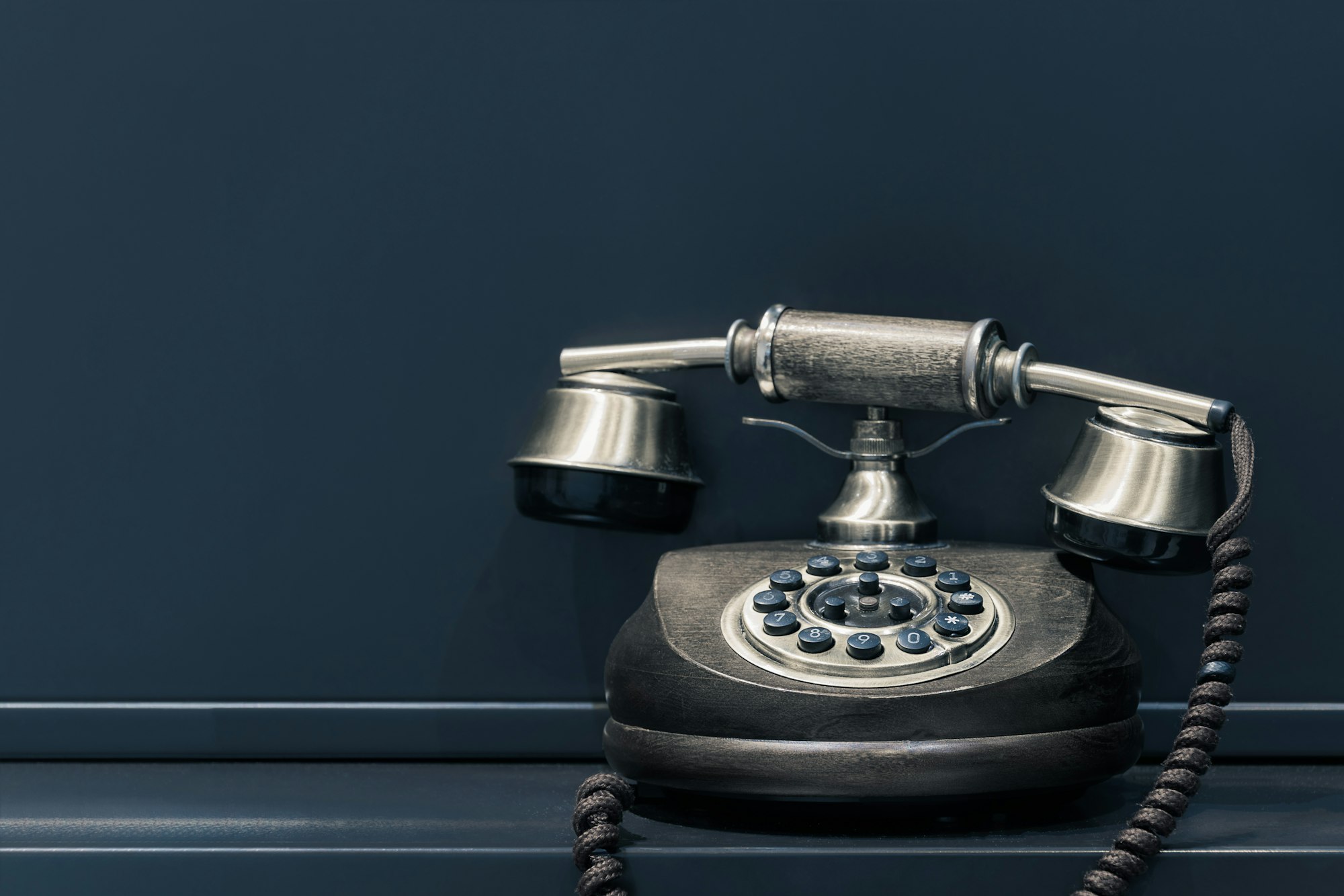 En gammel telefon på et mørkeblått skrivebord